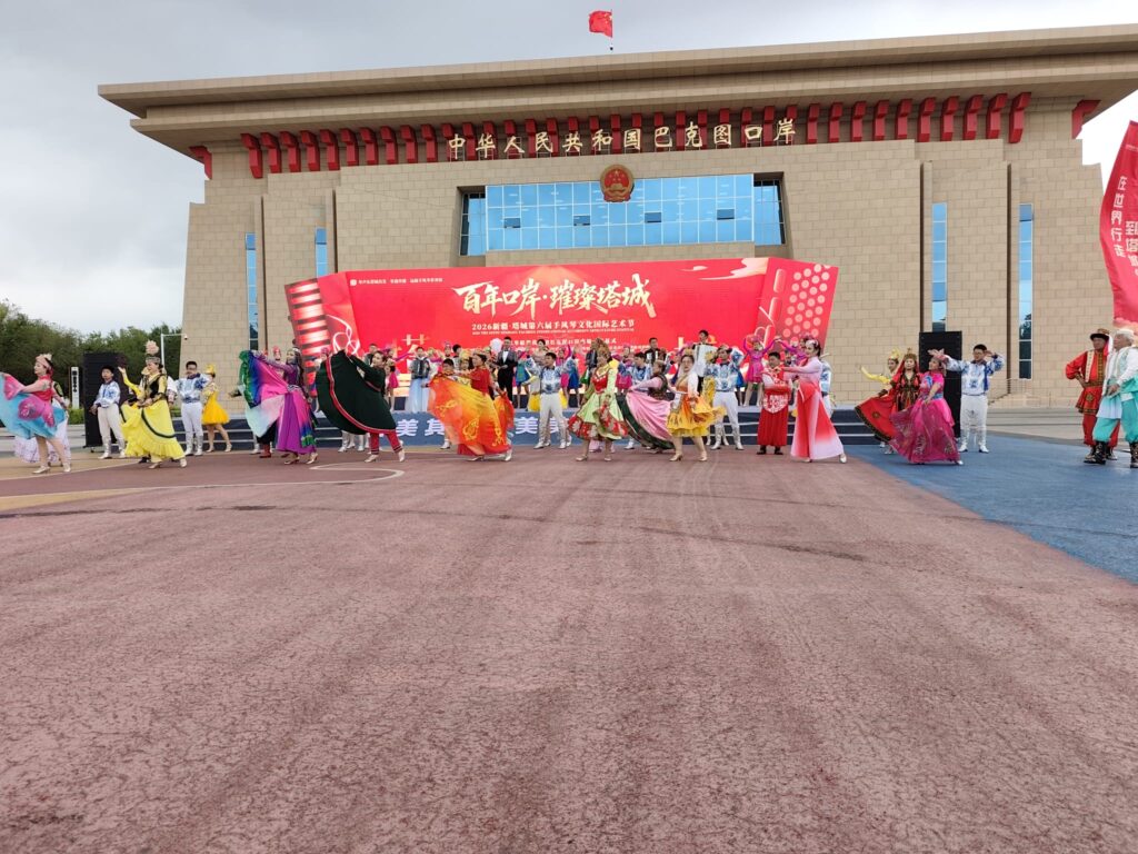 Dancers and musicians on the stage in front of the Tacheng border building.